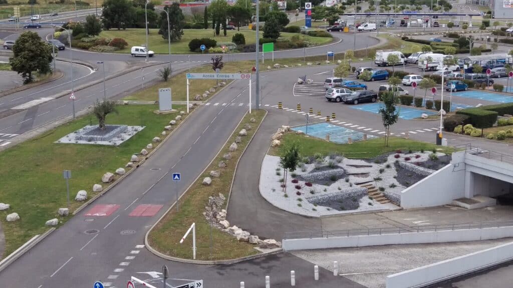 Accès parking Entrée 1 : Plan détaillé de la zone commerciale. Zone d'accès routier et parking commercial. Signalisation "Accès Entrée 1" avec barrières, rond-point et rampe d'accès souterrain.